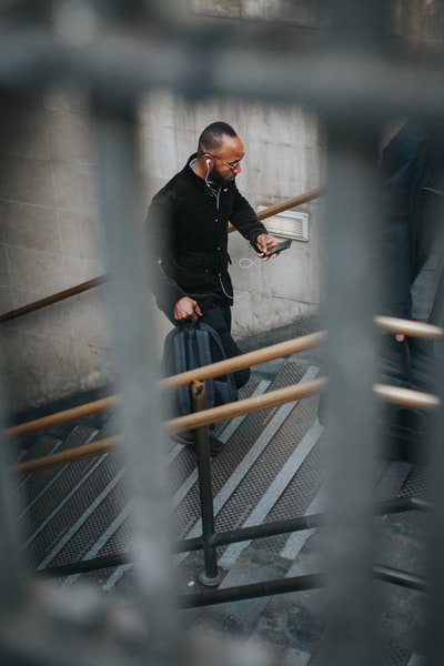 男子在楼梯上使用智能手机和背背包